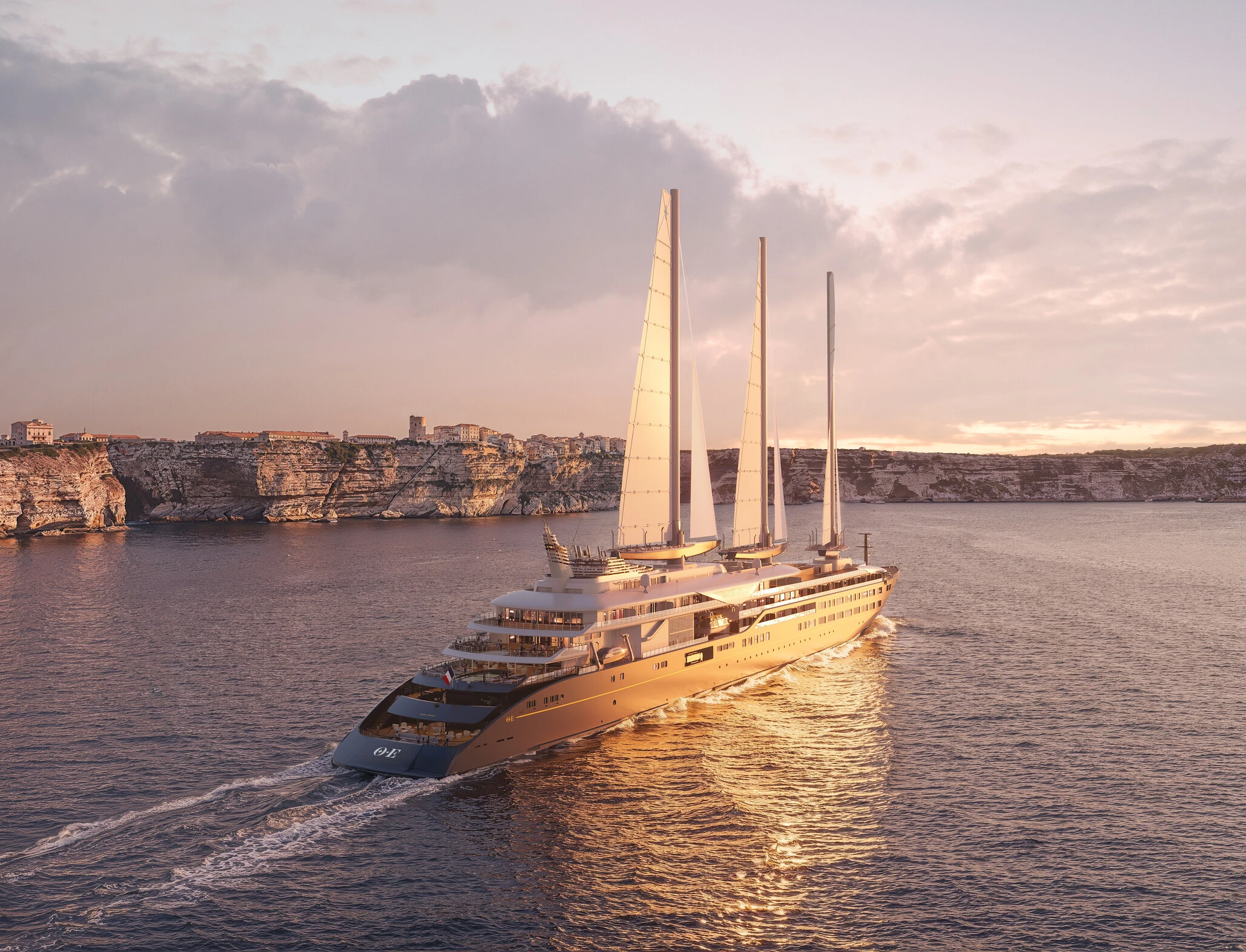 Three-masted sailing yacht Corinthian gliding past Bonifacio limestone cliffs at golden sunset 